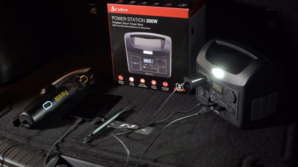 Cobra Power Station in the rear cargo area of an SUV at night with the "area light" turned on. We are charging a portable handheld vacuum, a phone, and a cordless power screwdriver simultaneously. Photo: Alex Hartman.